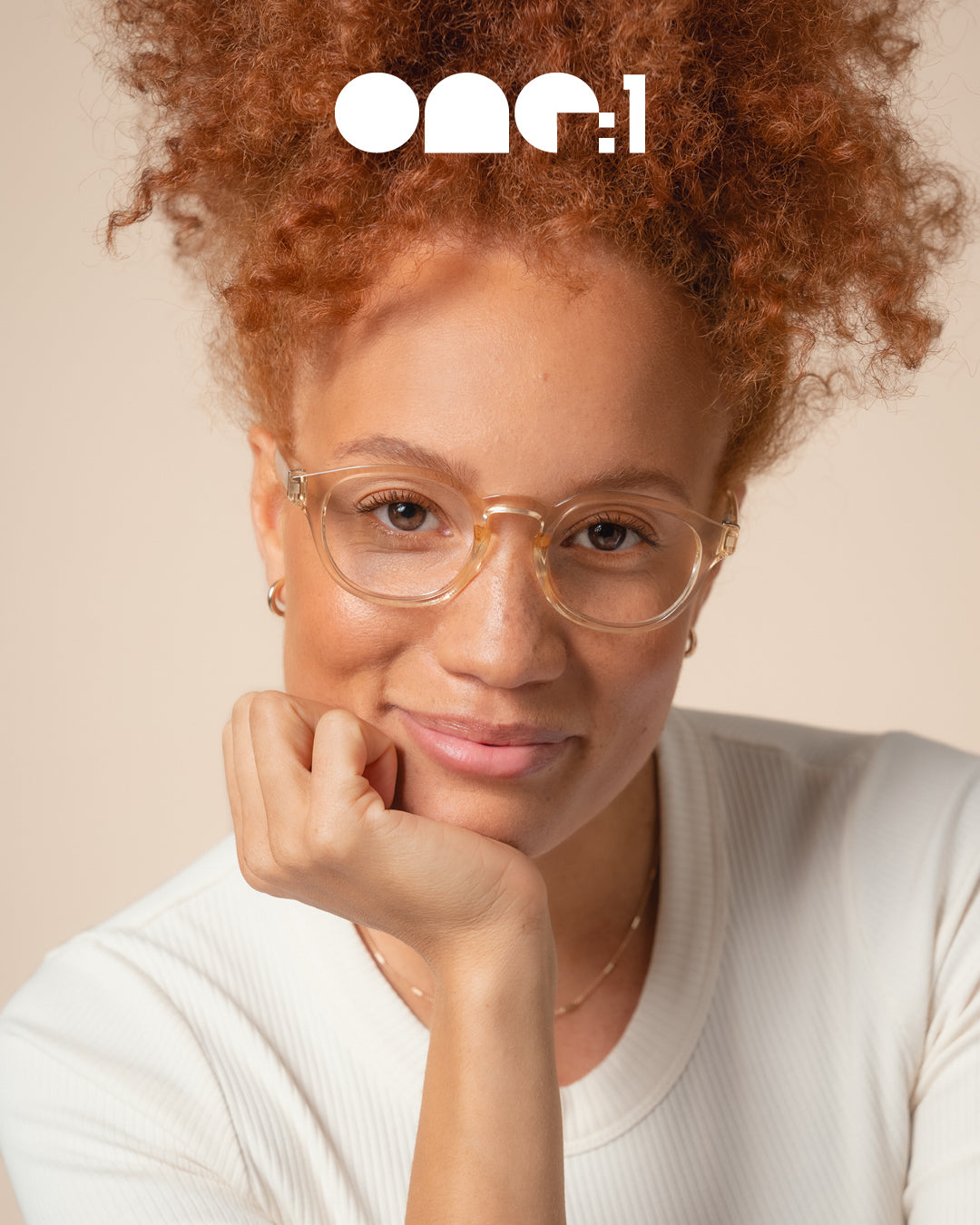 One:1 Readers campaign close-up of female model wearing sand-colored recycled plastic eyeglasses against plain background – sustainable luxury eyewear fashion photography.