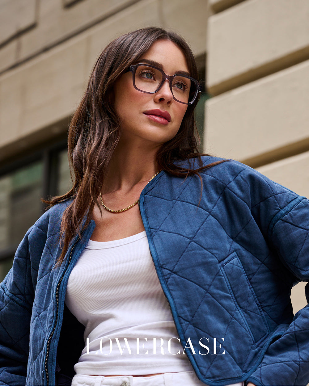 LOWERCASE Eyewear campaign featuring female model in purple acetate eyeglasses with blurred urban background – luxury women’s eyewear fashion photography.