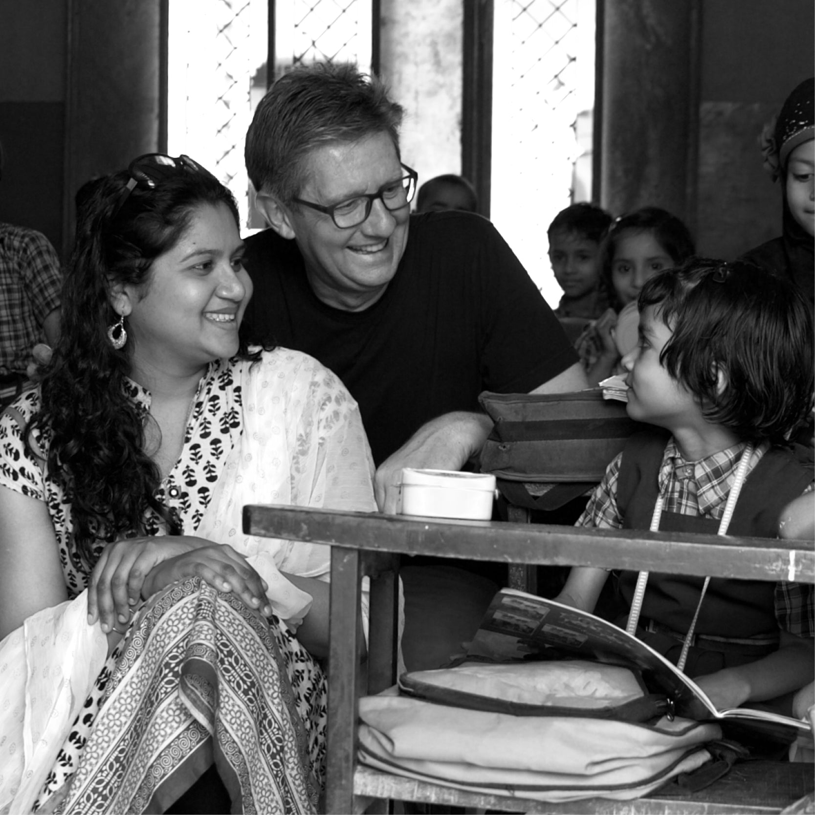 Photo of Alessandro Lanaro, Founder and CEO of HOUSE of MODO, smiling at a child and teacher inside a classroom in India—highlighting the Buy a Frame - Help a Child See program.