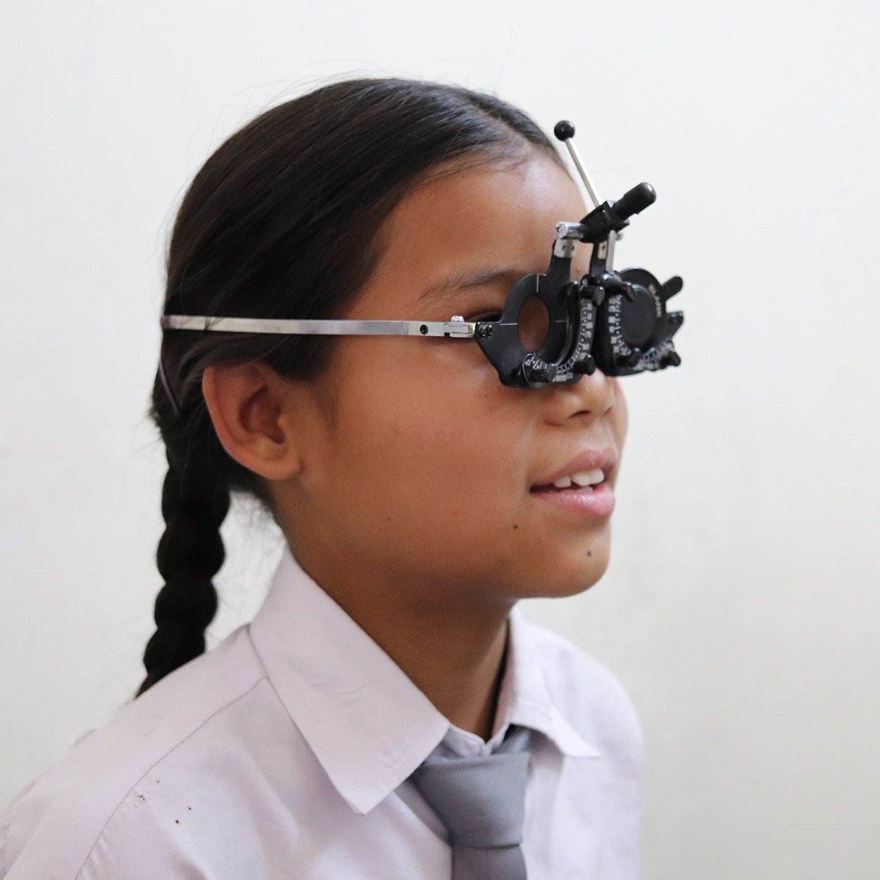 Close-up of a teenager undergoing an eye exam with a phoropter device during a vision screening.